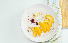 Muesli with yogurt in a plate with banana and peach pieces