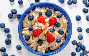 Овсяная каша в тарелке с ягодами черники и клубники 