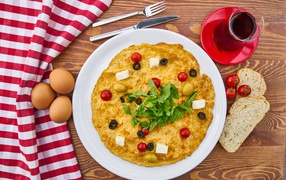 Омлет на столе с чаем, помидорами, яйцами и хлебом