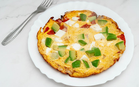 Omelet with avocado and slices of tomato on a white plate