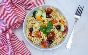 Pasta in a plate with vegetables on the table