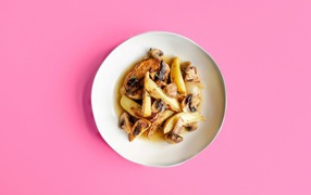 Картофель с грибами в тарелке на розовом фоне 