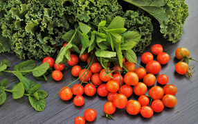 Red small tomatoes on a table with herbs