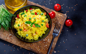 Рис с овощами на столе с маслом, зеленью и помидорами 