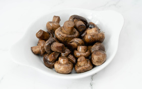 Roasted whole champignon mushrooms on a white plate