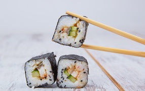Rolls with fish and cucumber on a table with chopsticks