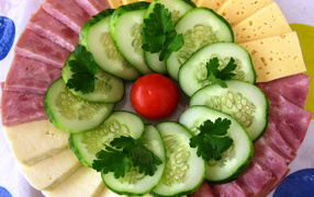 Sliced cheese, cucumbers and ham on a plate