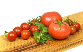 Маленькие и большие помидоры на деревянной доске 