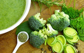 Soup puree on the table with broccoli, herbs and onions