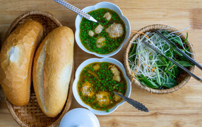 Soup with meatballs on the table with bread and salad