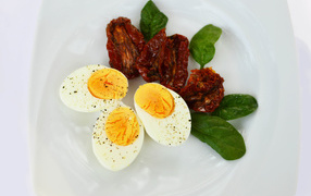 Sun-dried tomatoes on a plate with basil and boiled eggs