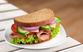 Tasty appetizing sandwich with vegetables and ham on a plate