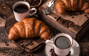 Две чашки кофе на столе с рогаликами и зернами 