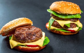 Two delicious hamburgers with a juicy cutlet on a gray background