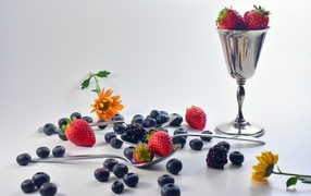 Ежевика, черника и клубника на столе с ложками