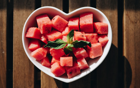 Нарезанный кубиками арбуз в белой тарелке в форме сердца