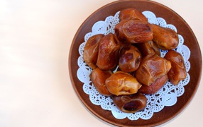 Сушеные финики в деревянной миске на белом фоне