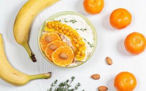 Мюсли с облепихой, бананом и апельсином на столе с фруктами