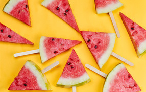 Кусочки арбуза на палочках на желтом фоне