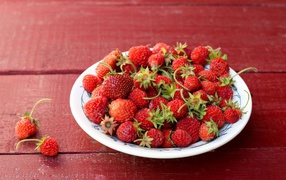 Тарелка со спелой домашней клубникой на столе