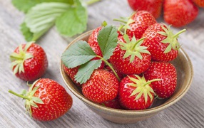 Красная спелая сладкая клубника в тарелке с зелеными листьями