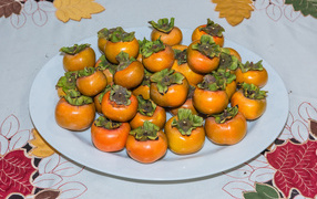 Спелый фрукт хурма на большой белой тарелке 