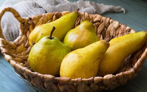 Спелые груши лежат в корзине на столе