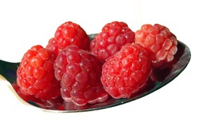 Спелая красная малина в ложке на белом фоне 