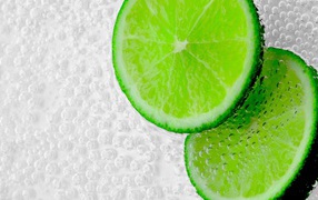 Два куска лайма в пузырях в воде 