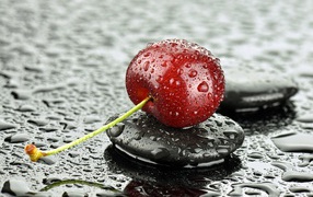Мокрая черешня лежит на черном камне