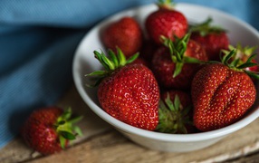 Белая тарелка со спелой красной клубникой