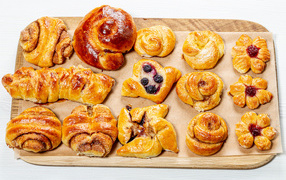 Different fresh pastries on a blackboard on a white background