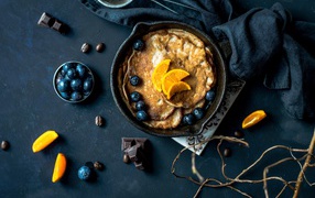 Блины с ягодами черники и апельсинами на столе 