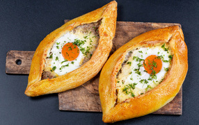 Two large fresh khachapuri with egg on the board