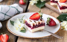 Кусок пирога на тарелке с клубникой и цветами жасмина