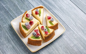 Аппетитный чизкейк с ягодами нарезан кусками на тарелке 