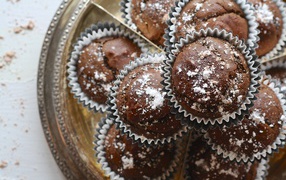 Аппетитные кексы с сахарной пудрой на столе 