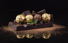 Плитки черного шоколада с конфетами на столе 