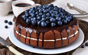 Шоколадный пирог с ягодами черники  на столе с кофе