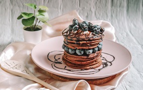 Шоколадные оладьи с ягодами черники на белой тарелке