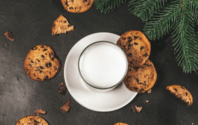 Печенье с шоколадом на столе со стаканом молока 