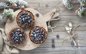 Кексы с кремом и ягодами черники на столе с чайными ложками