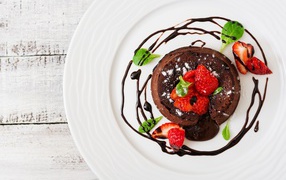 Вкусный десерт на белой тарелке с клубникой и шоколадом