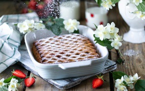 Вкусный клубничный пирог с сахарной пудрой на столе с цветами жасмина