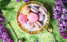Разный десерт макарон на столе с цветами сирени 