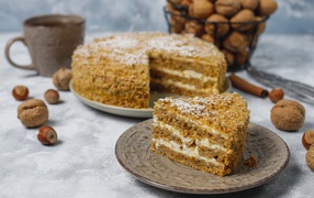 Торт медовик на столе с орехами и чашкой кофе