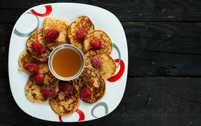 Оладьи на тарелке с клубникой и медом