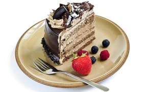 Кусок торта с ягодами на тарелке на белом фоне