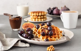 Сладкие вафли на тарелке с инжиром и виноградом