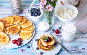 Вкусные оладьи на столе с ягодами черники, творогом и молоком